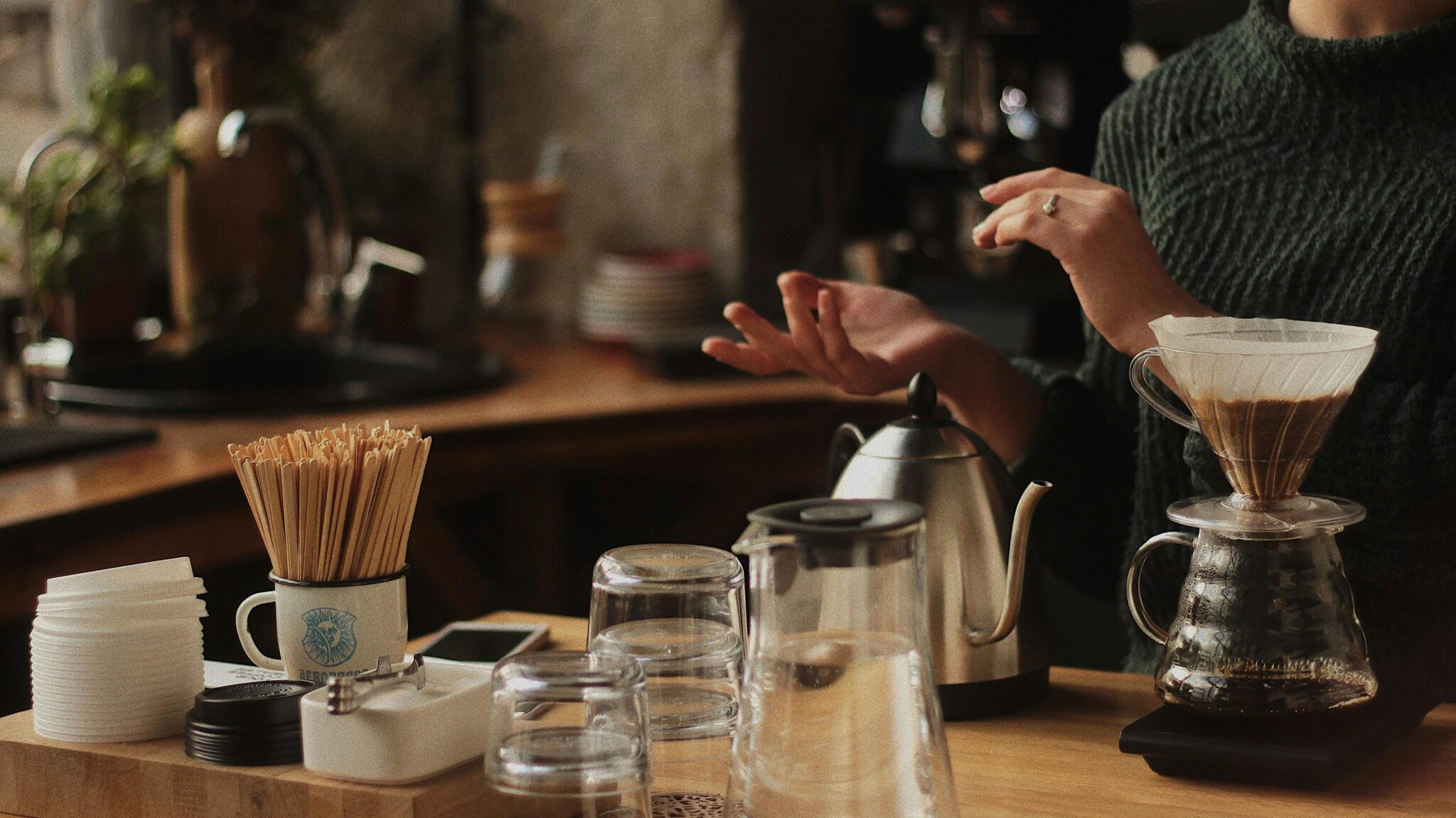 Artisan coffee brewing in a cozy café with a barista using pour-over method.